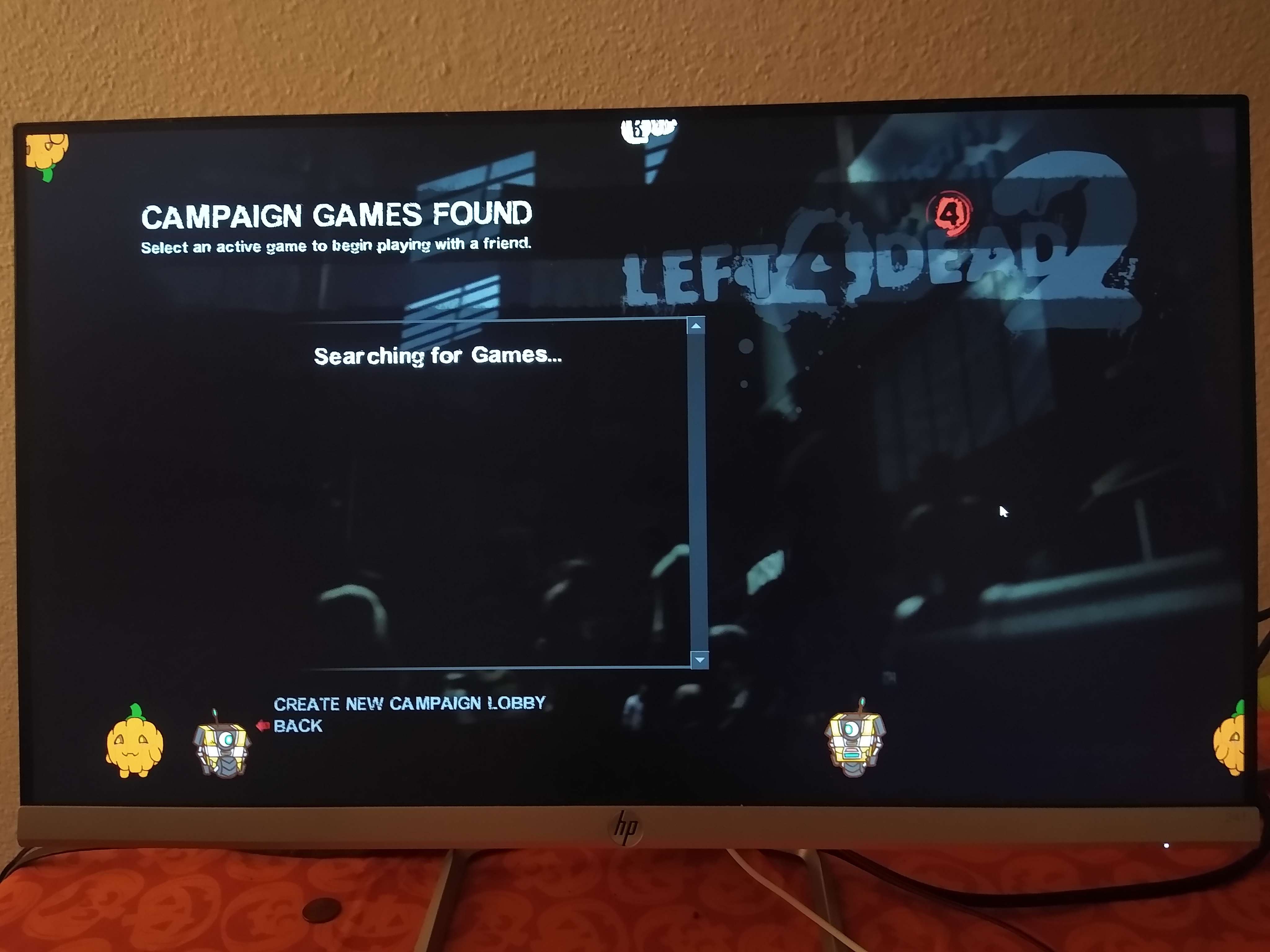 Picture of a computer screen. On the screen is the main menu for Left for Dead Two, with shimijees walking around the screen. There are three types of shimijees, a pumpkin, Claptrap from Borderlands, and Benrey from HLVRAI